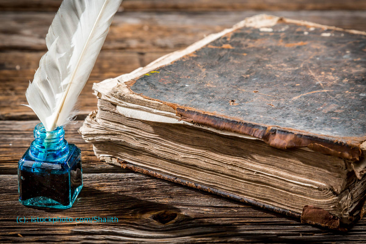 altes Buch mit Feder und blauem Tintenfass